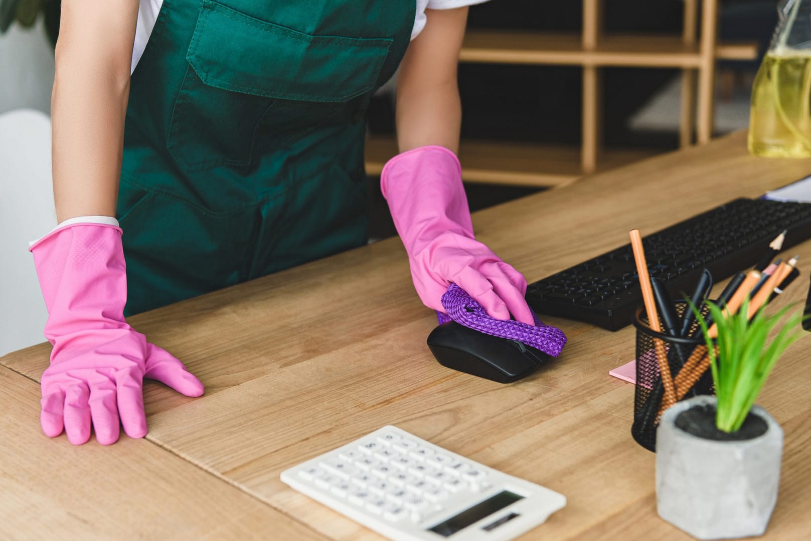 cropped shot of woman in rubber gloves cleaning office table - Reliable Commercial Cleaning